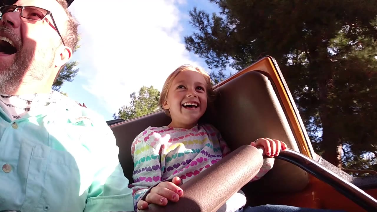 Young girl smiles beside her father on the ride.