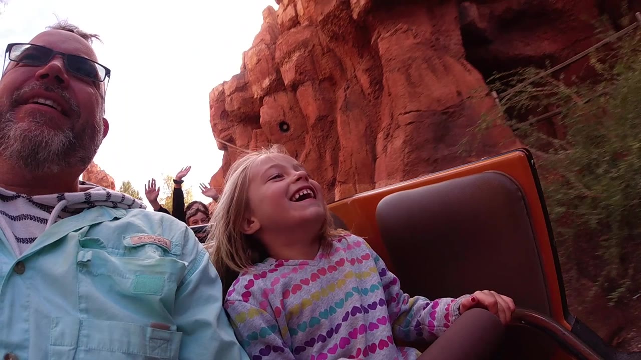 Man and young girl laughing as the ride passes red canyon rock.
