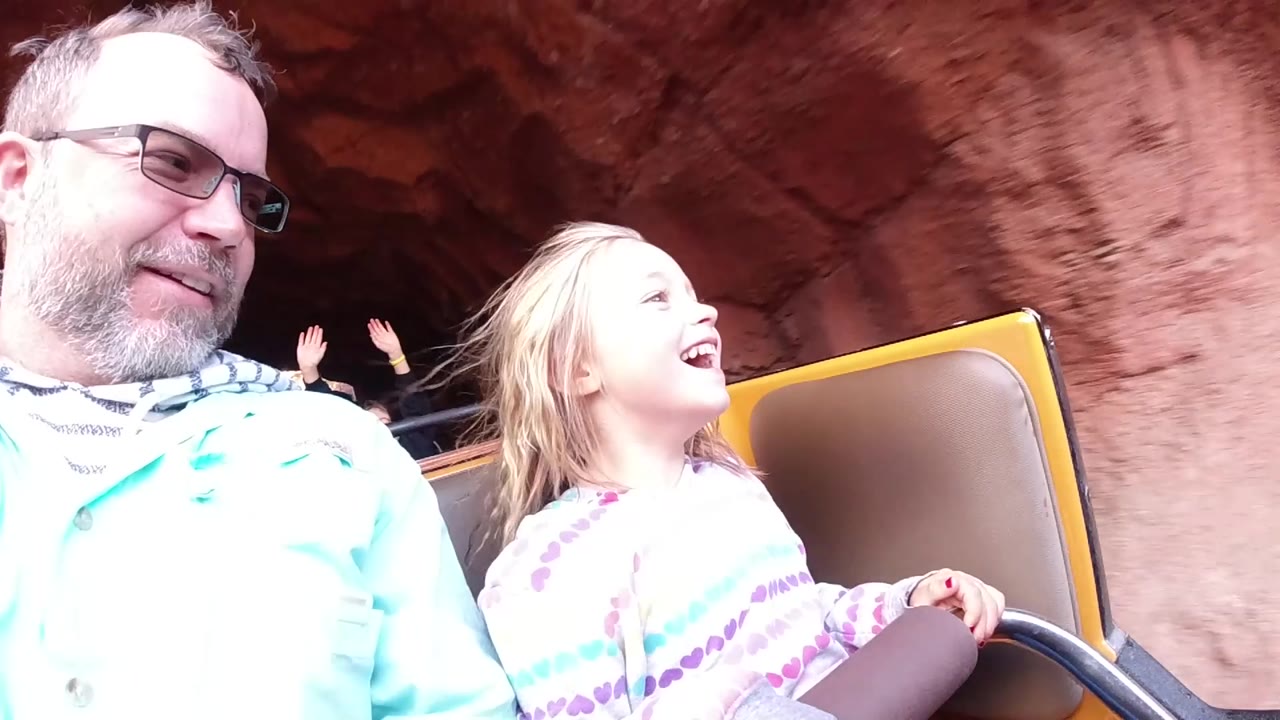 Child laughing in a ride car with rockwork behind her.