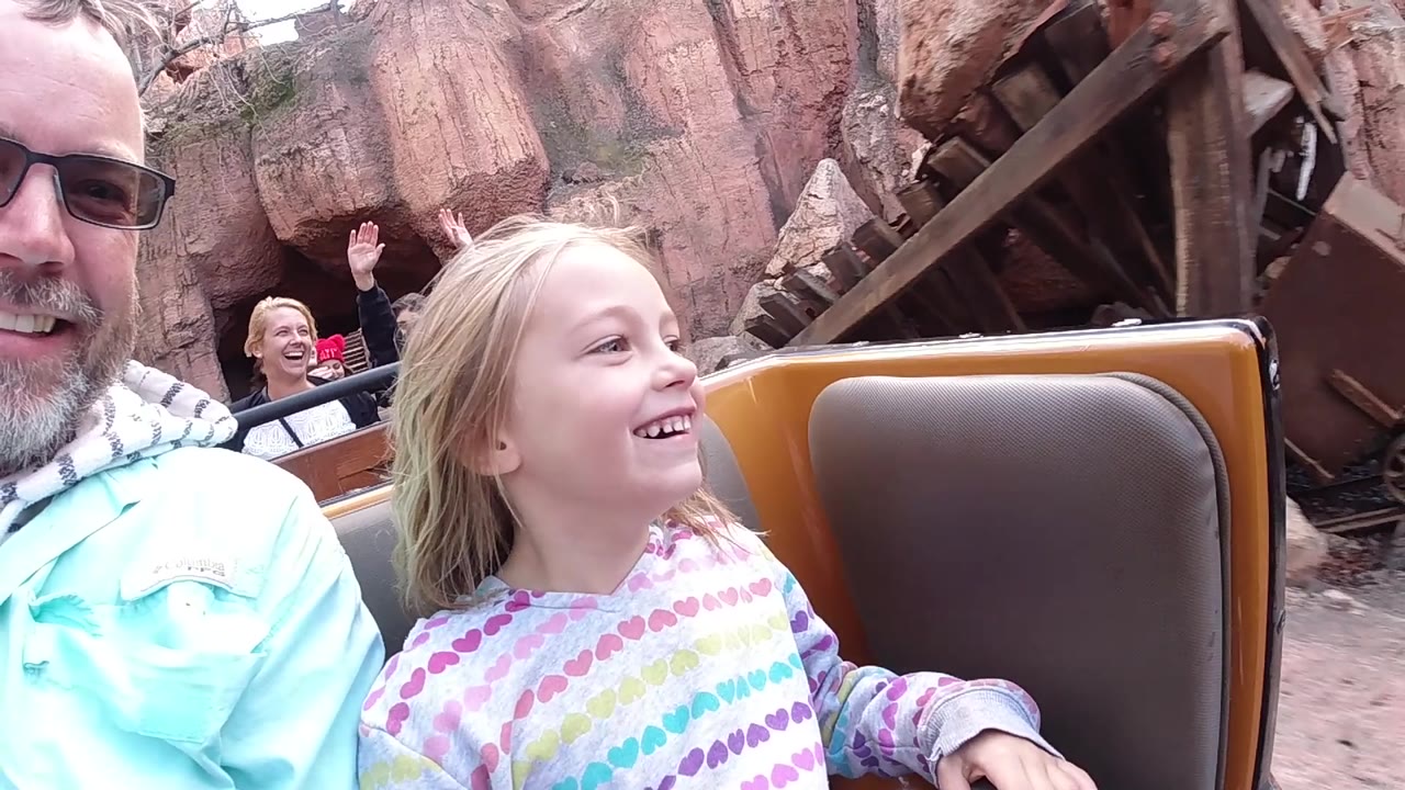 Close roller coaster reaction with girl, man, and rider behind