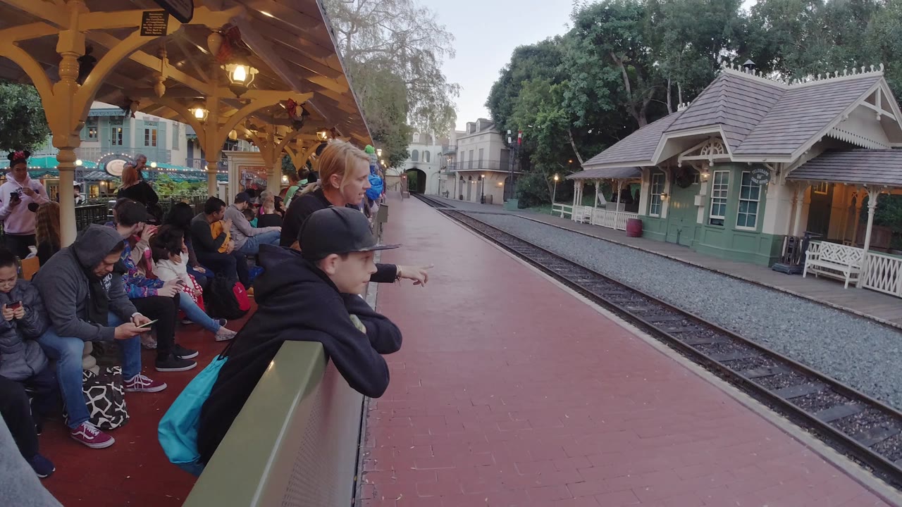People seated on benches and ledges at a train platform.