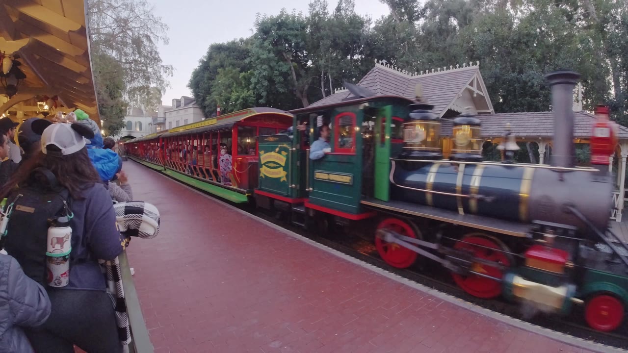 Locomotive passing in front of waiting park guests.