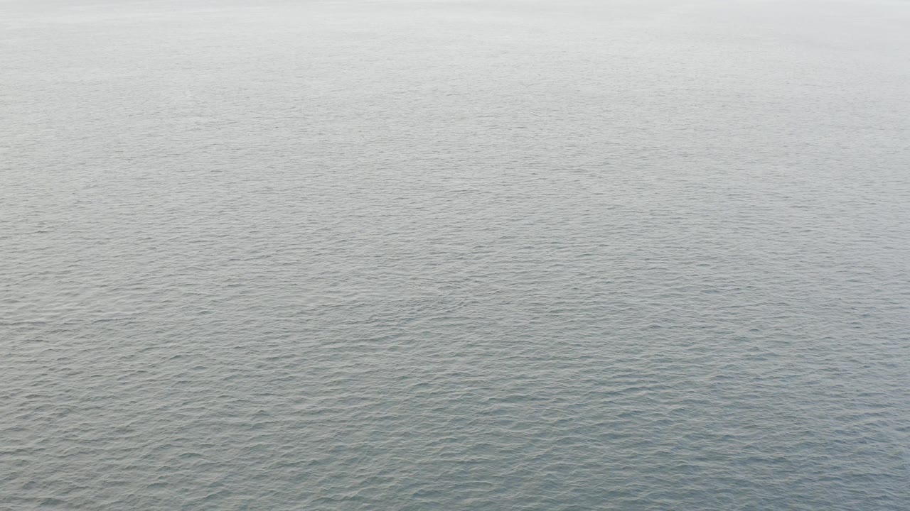 Aerial coastal water frame in Baja California Sur, Mexico, where gray-green rippled sea fills nearly the whole view and no visible people appear.