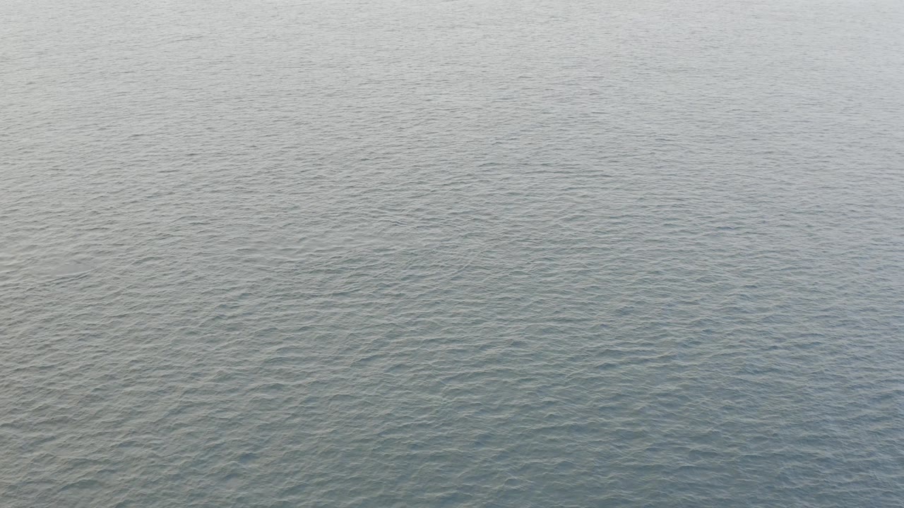 Open blue-gray water in Baja California Sur shows low rolling wave patterns across the middle of the frame, with no visible people or vessels.