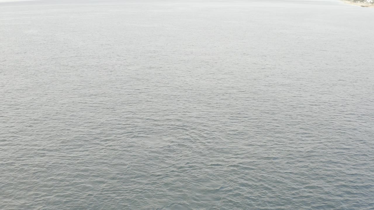 Aerial view in Baja California Sur showing a broad sheet of lightly rippled ocean, a barely visible shore strip at the top, and no visible people.