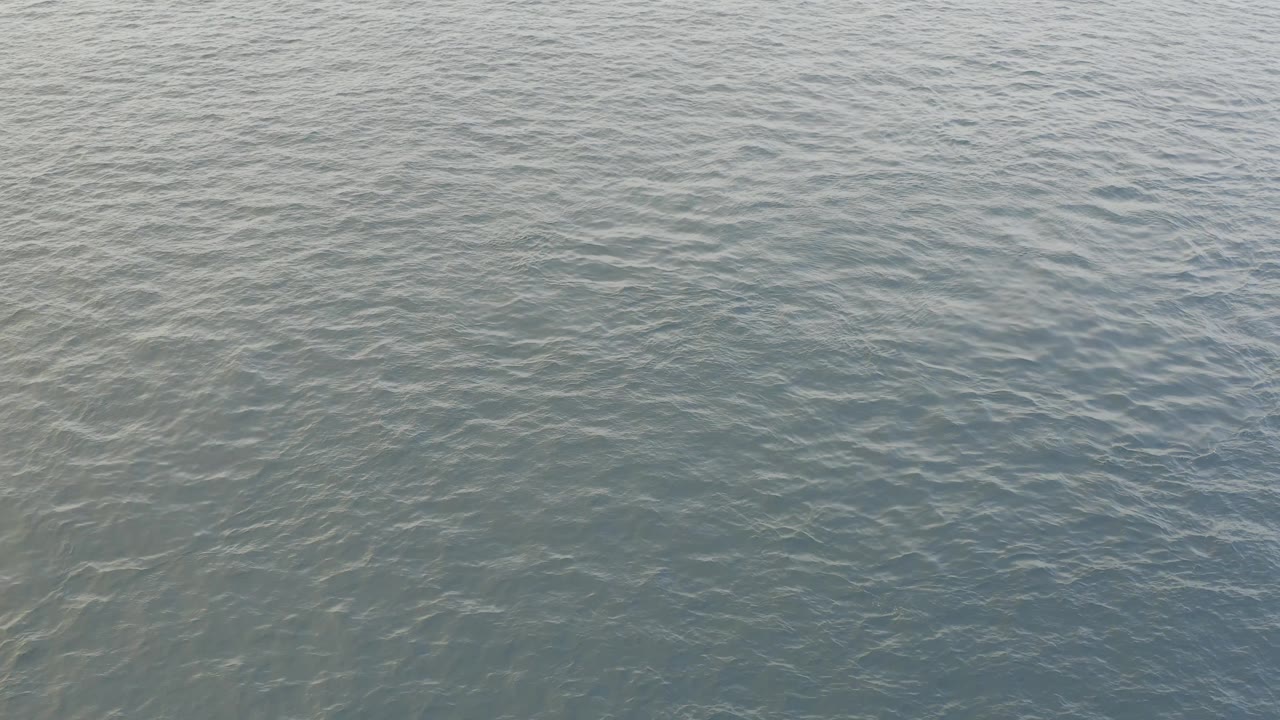 Calm ocean water with diagonal ripples and muted daylight reflection.