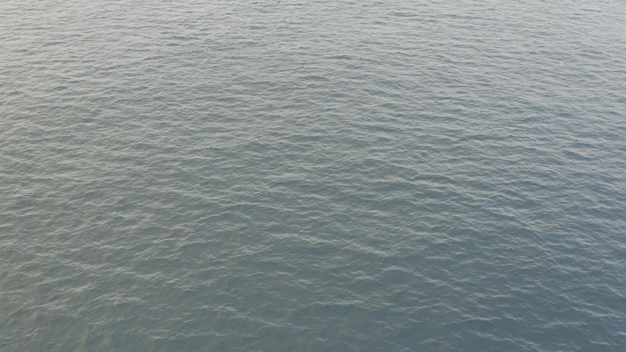 Overhead frame of open Baja California Sur ocean with pale daylight on low ripples and no visible people or vessels.