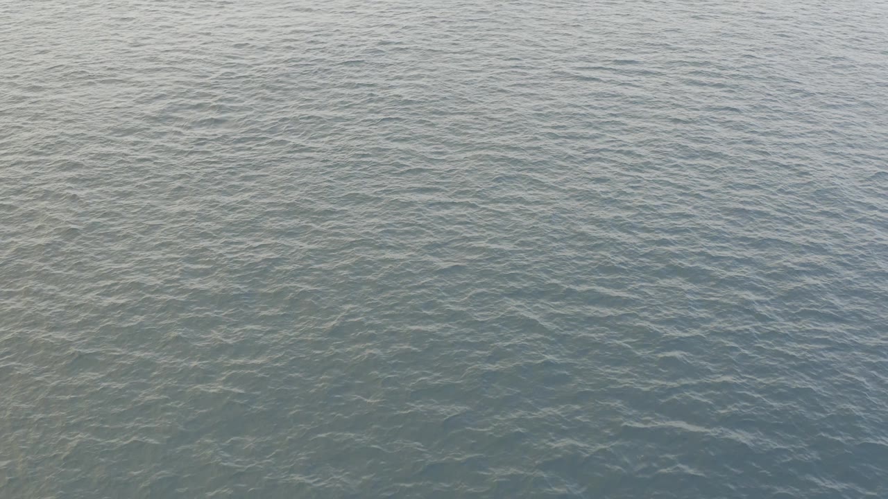 Second frame shows the water surface slightly darker through the center, with fine ripples crossing the Baja California Sur ocean and no visible people.