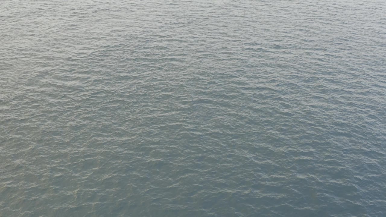 Third frame holds on a soft hazy blue green water surface in Baja California Sur, Mexico, with light ripple lines and no visible people.