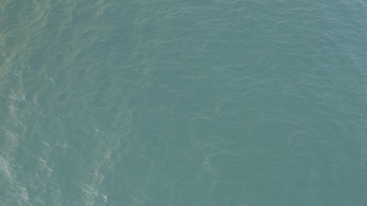 Overhead view of sea-green water in Baja California Sur with faint surface ripples, pale underwater streaks, and no visible people.