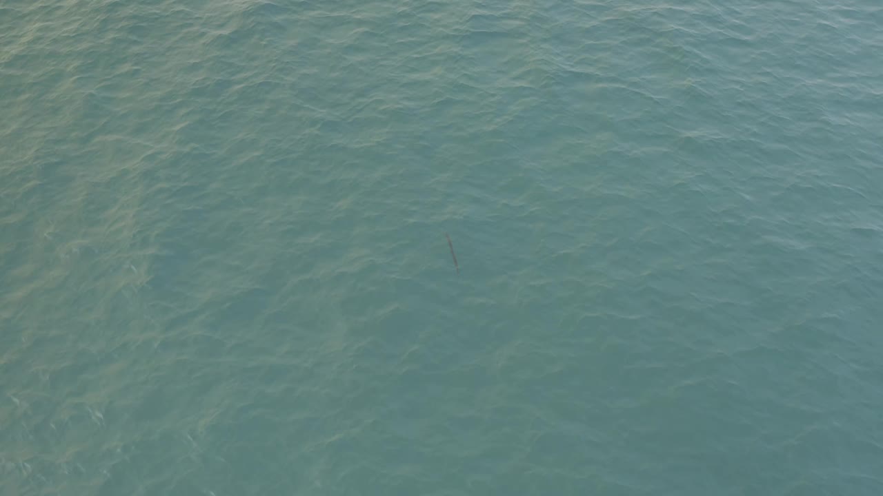Blue-green ocean water in Baja California Sur shows faint diagonal wave streaks across an uninterrupted surface with no visible people.