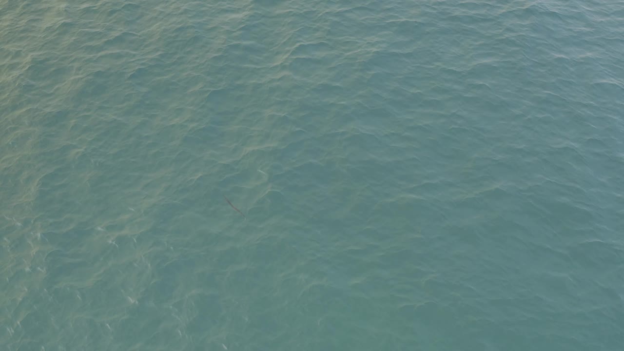 Aerial frame over turquoise-green ocean in Baja California Sur, Mexico, showing denser ripple patterns near the center and no visible people.