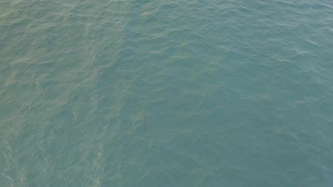 Aerial view over gray blue water in Baja California Sur Mexico, where pale streaks shift across the upper left and no visible people appear.