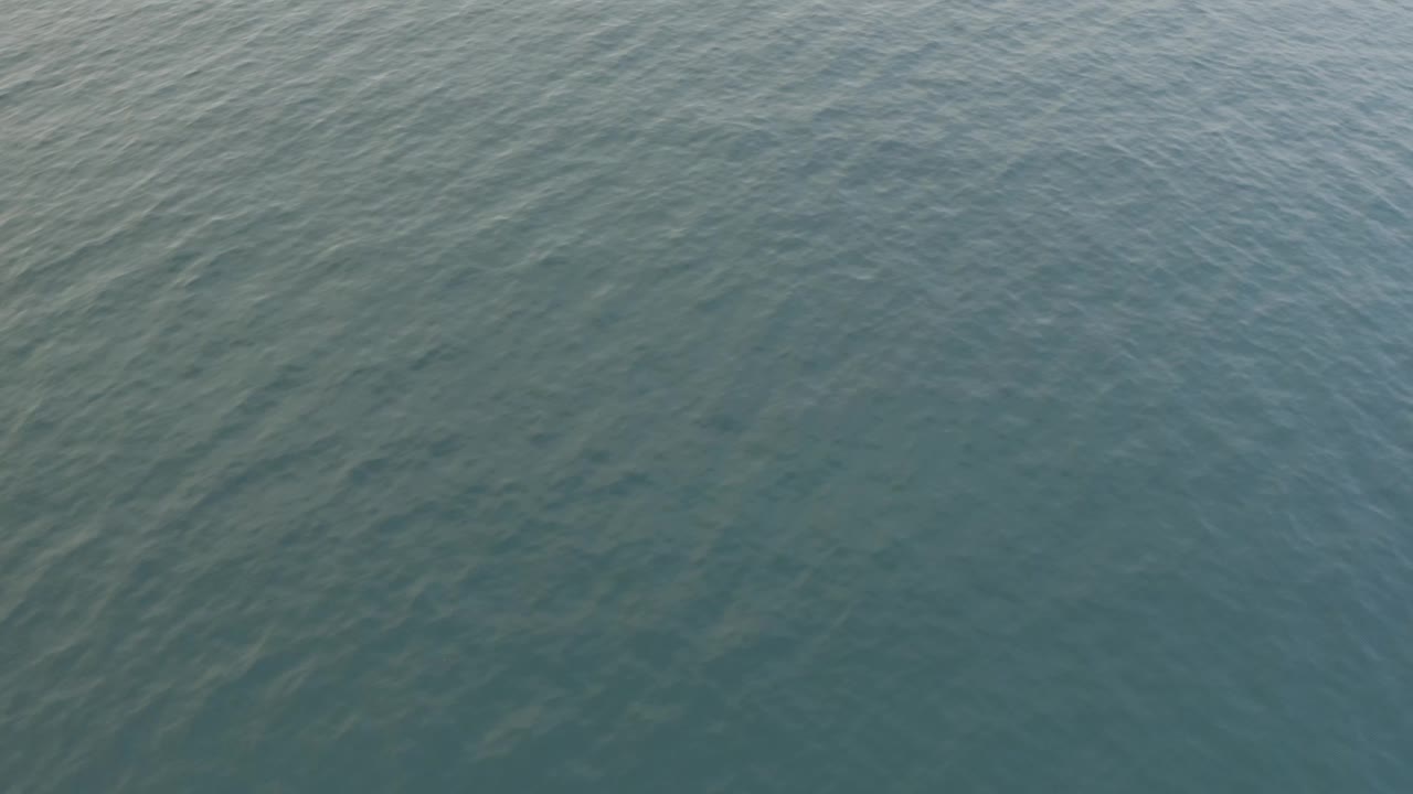 Aerial view of open Baja California Sur water with faint wave streaks, slight darker tones, and no visible people.