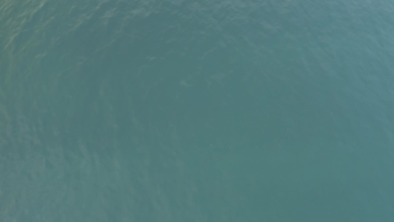 Soft teal water surface with low-contrast ripple lines.