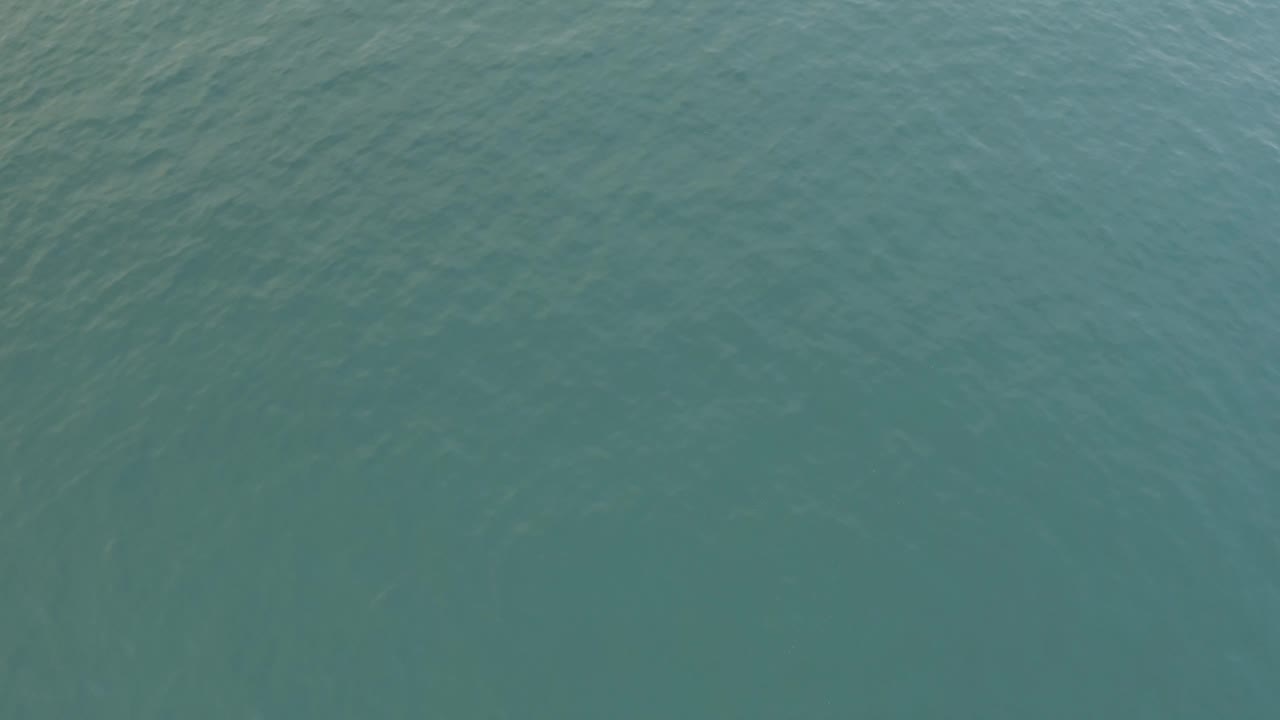 A high view over Baja California Sur ocean water shows muted blue green color, faint diagonal ripple marks, and no visible people.