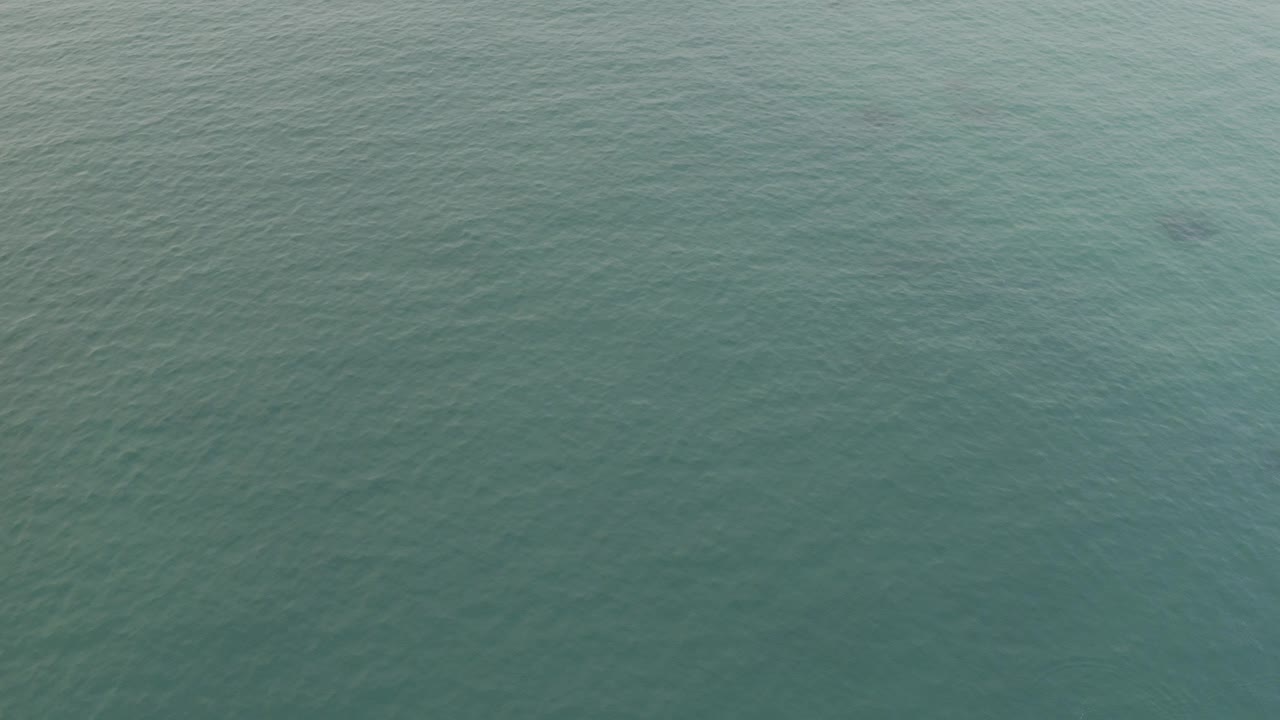 Turquoise ocean surface seen from above near a pale shoreline
