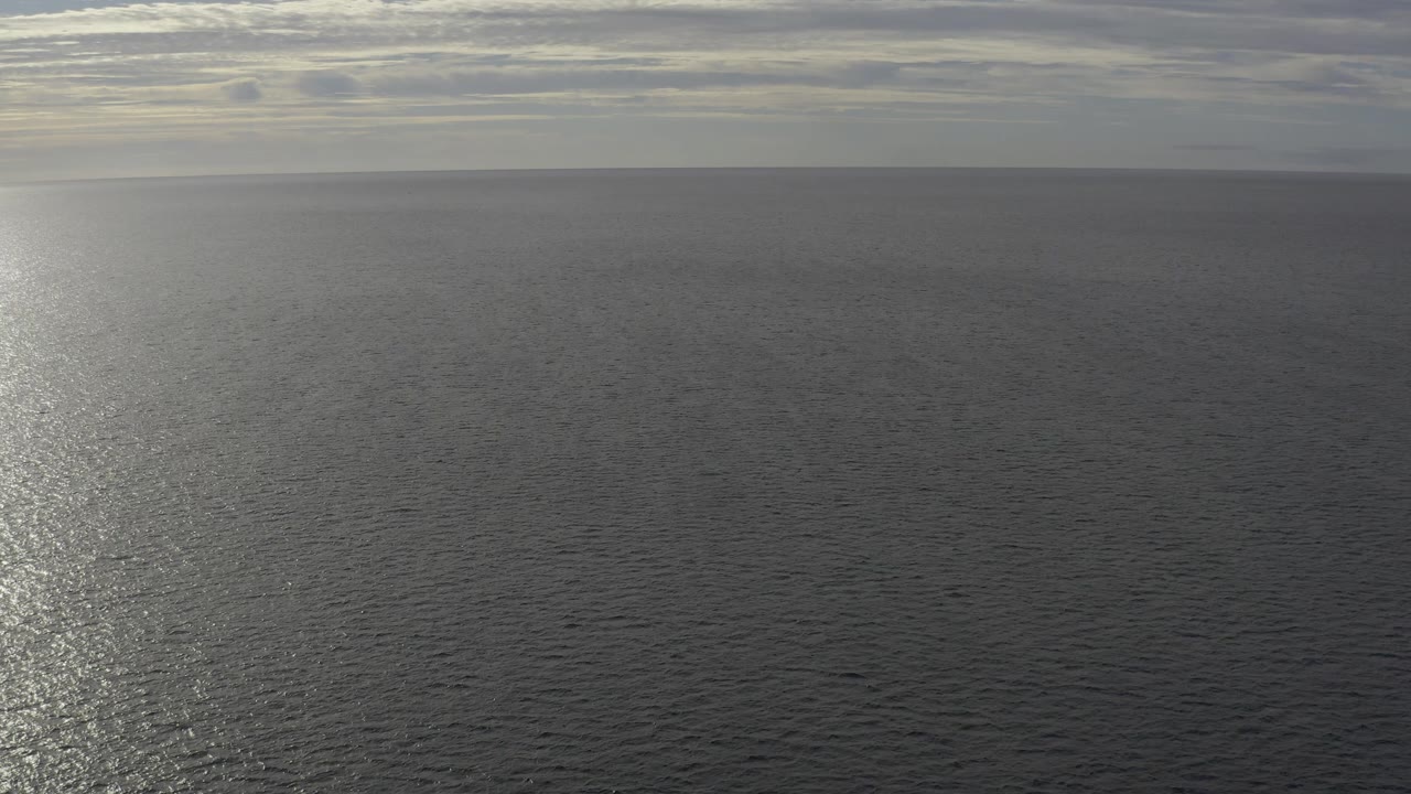 Flat ocean horizon with a bright column of reflected light.