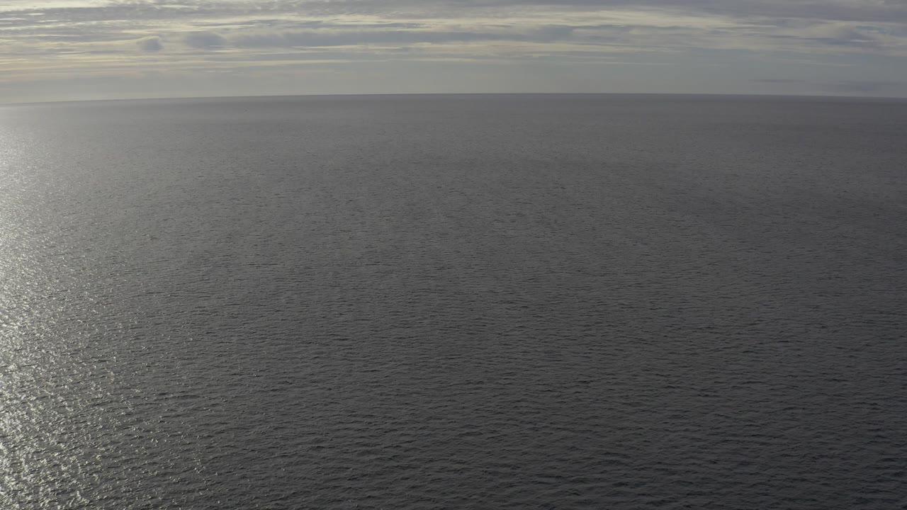 Open water in Baja California Sur Mexico with a soft cloudy horizon and a bright sun reflection slightly left of center, no visible people.
