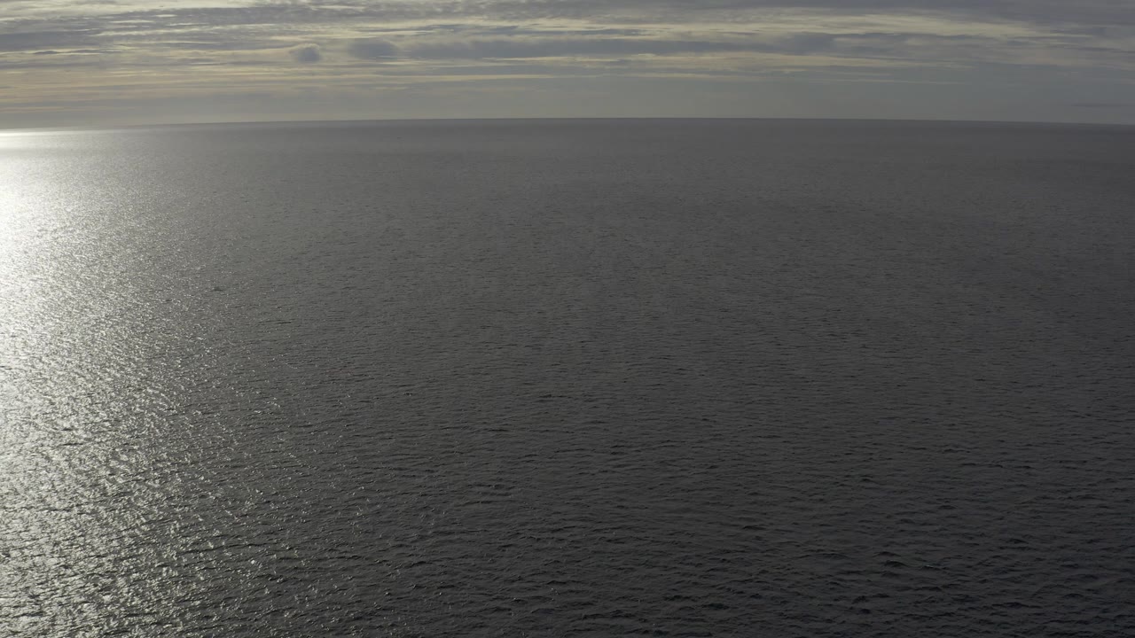 Gray ocean horizon with sunlight reflecting on rippled water
