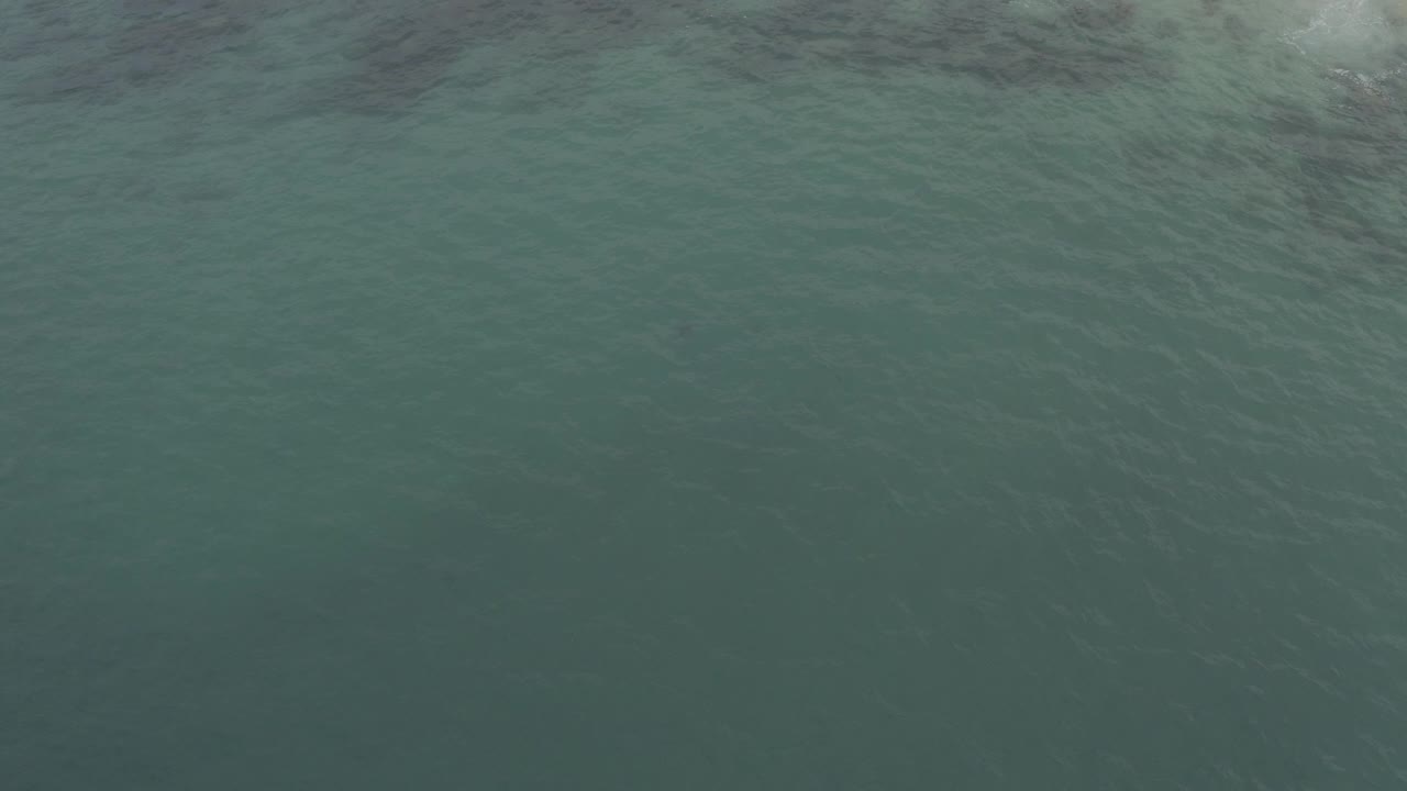 Aerial view over green-blue ocean water in Baja California Sur, Mexico, with subtle ripples across the surface and no visible people.