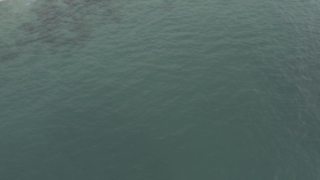 Aquamarine water in Baja California Sur, Mexico, passes over submerged rocks with white foam gathered near the top of the frame and no visible people.