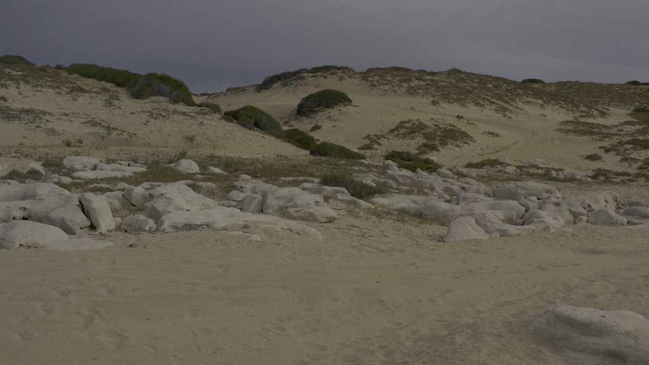 A similar Baja California Sur beach view shows the rock field and dune ridge shifted across frame, with no visible people or buildings.