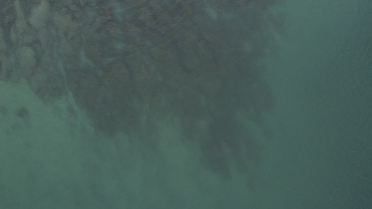 Green ocean water with dark reef shapes beneath the surface.