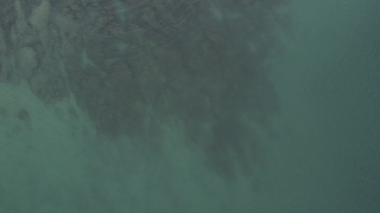 Green-blue water fills the frame as darker reef patterns sit below the surface in Baja California Sur, Mexico, with no visible people.