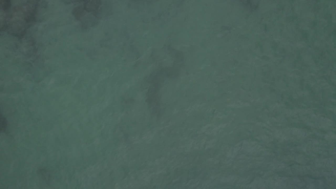 Muted green-blue ocean water seen from above in Baja California Sur Mexico, with darker patches more noticeable along the left side and no visible people or vessels.