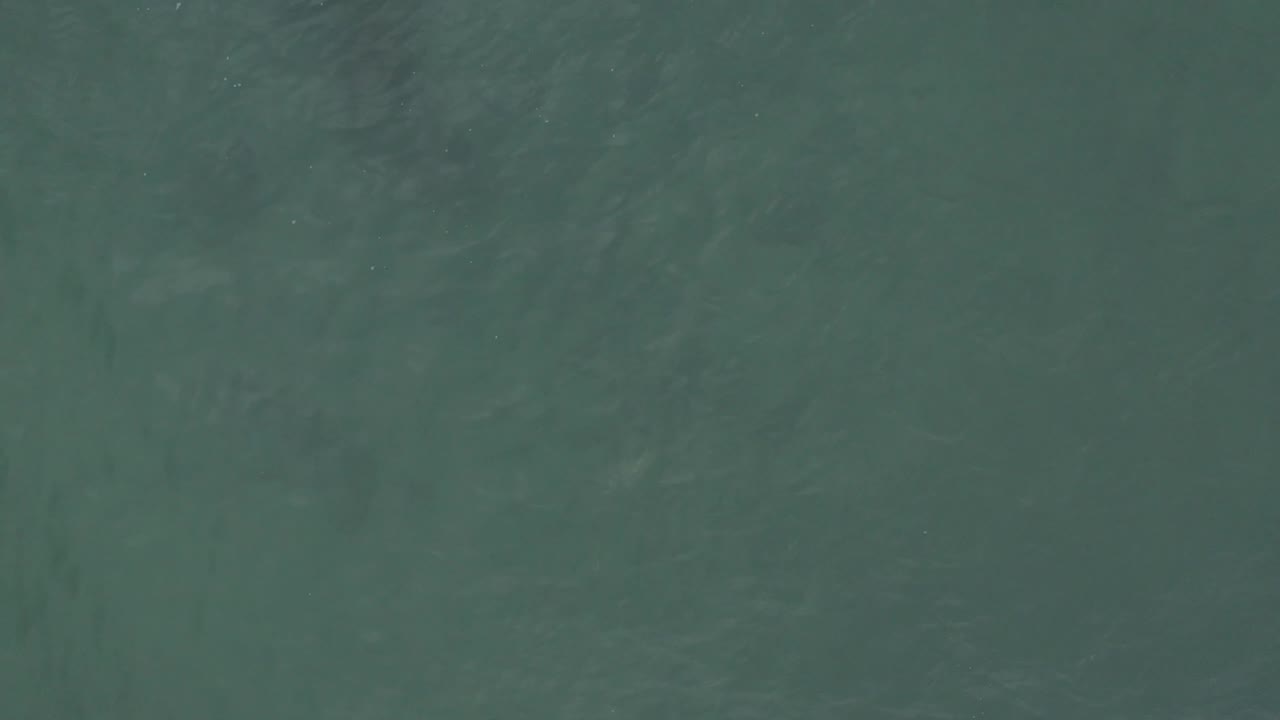 Top-down teal sea surface in Baja California Sur, Mexico, with slightly darker patches in the wave pattern and no visible people.
