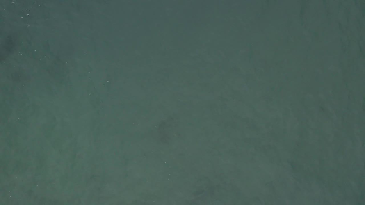 Calm teal water in Baja California Sur, Mexico, shows darker subsurface patches across the frame and no visible people.