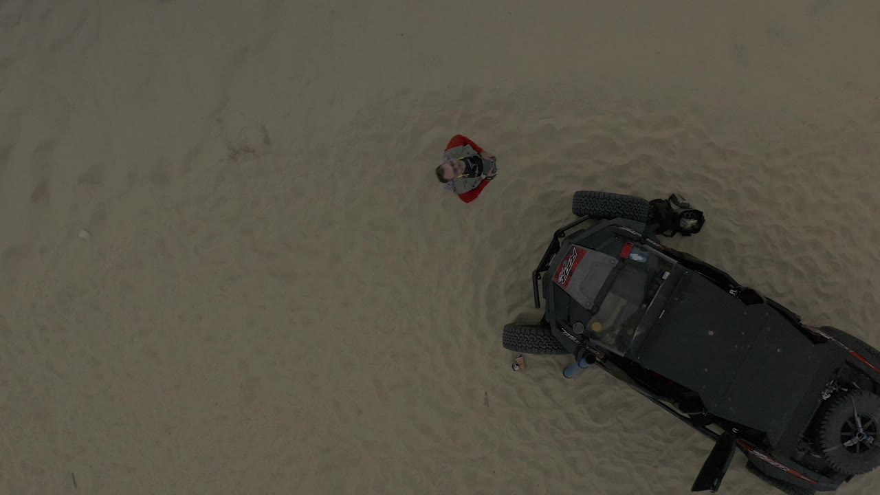 Overhead Baja California Sur Mexico frame with the off-road vehicle cropped at the right edge and the man standing apart in pale water near the top center.