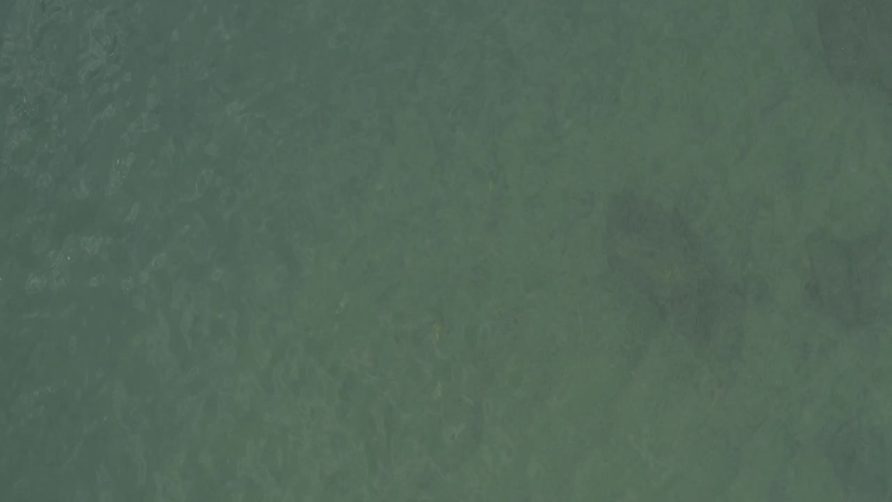 Top-down Baja California Sur ocean frame with diffuse wave marks across green water and no visible people.