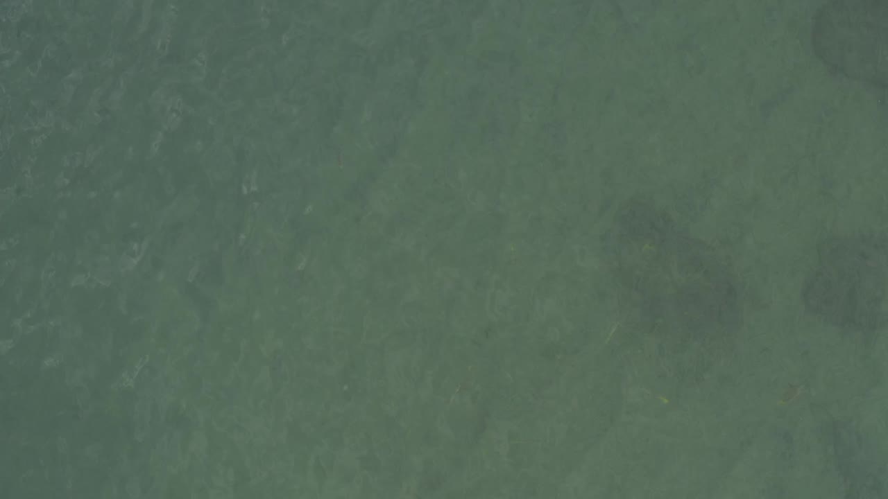 Aerial view of Baja California Sur ocean water with soft darker areas under the surface and no visible people.