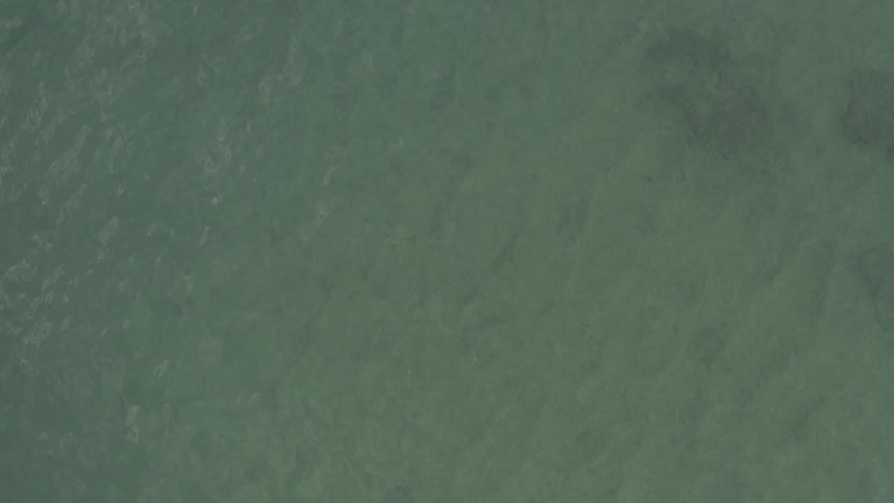 Mid-clip overhead water view in Baja California Sur, Mexico, showing faint wave patterns across a blue-green sea surface with no visible people.
