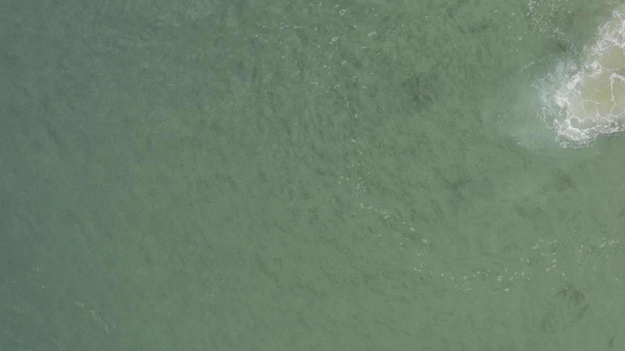 Green ocean water with white foam near the upper right edge.