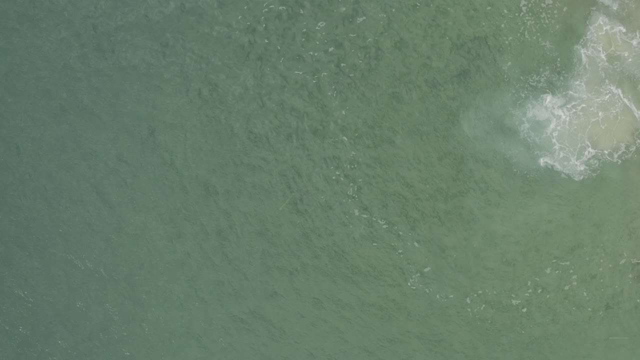 Overhead view of green ocean water in Baja California Sur, Mexico, with a small white foam break near the upper right and no visible people.