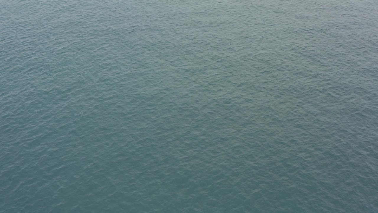 Open Baja California Sur sea surface fills the frame, with slightly darker blue-green ripple bands and no visible people.