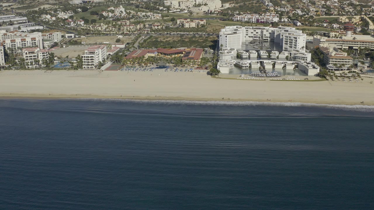 Aerial view of dark ocean, pale beach, and beachfront buildings