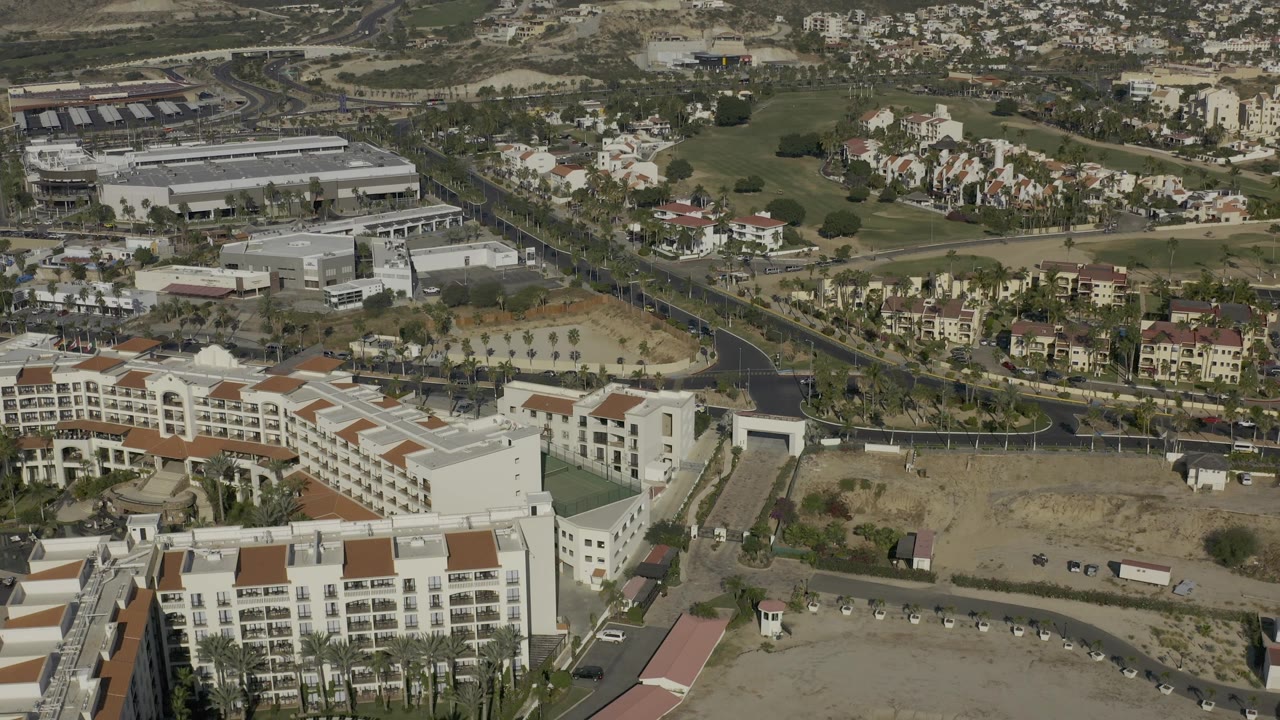 Drone-like aerial view of resort blocks, roads, golf fairway, and nearby housing.