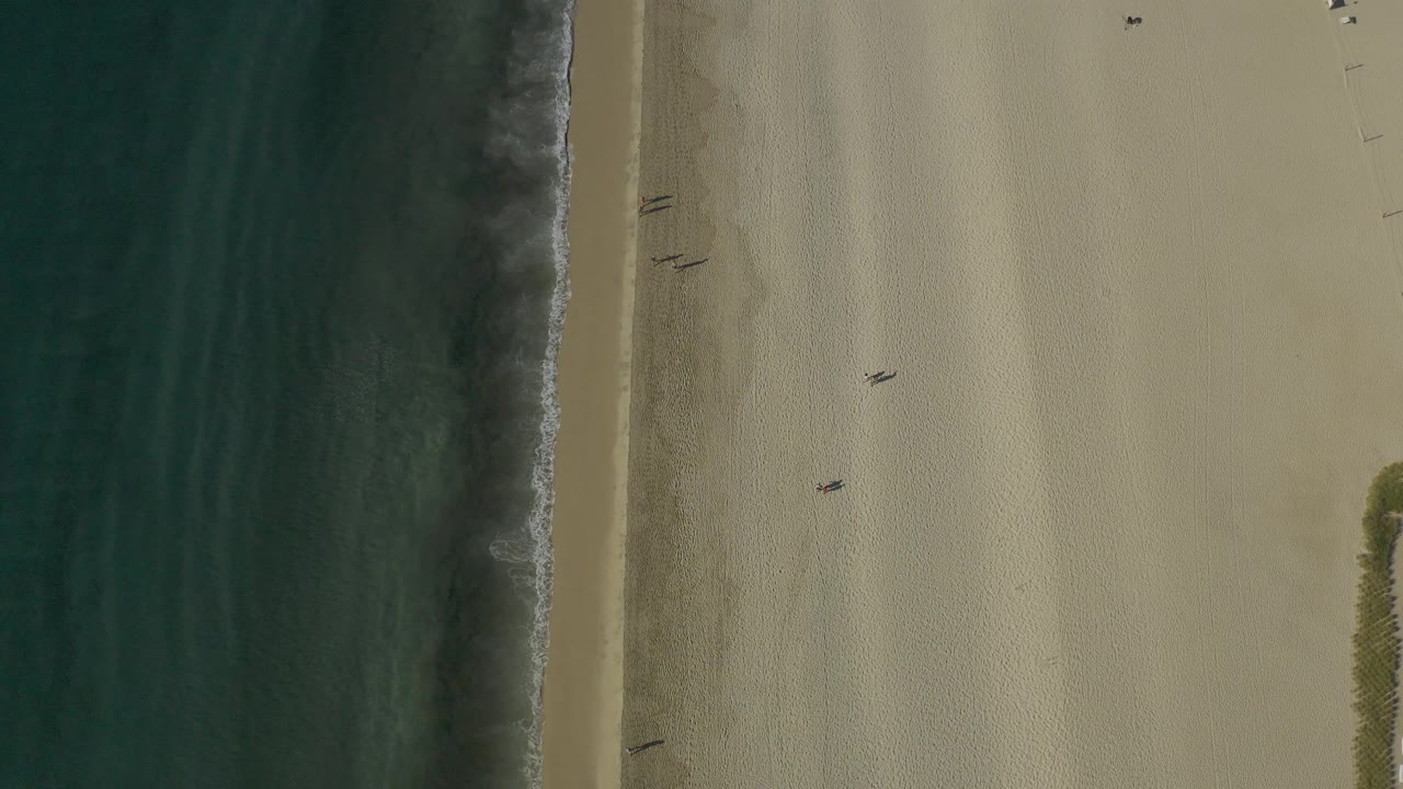 Beach from above with surf line and a few people on sand.
