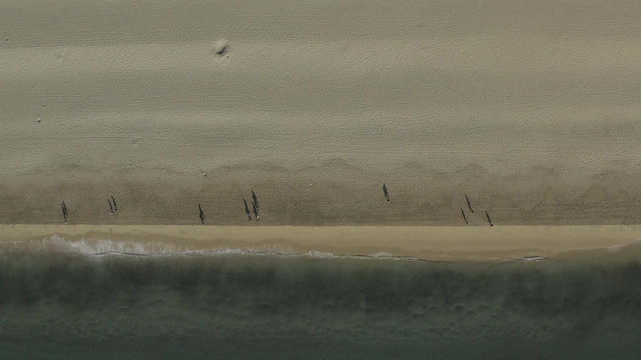 Overhead sand and ocean bands with tiny beach walkers.