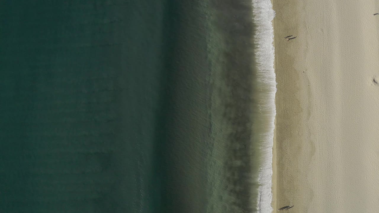 Aerial shoreline with a wave edge running along the beach.