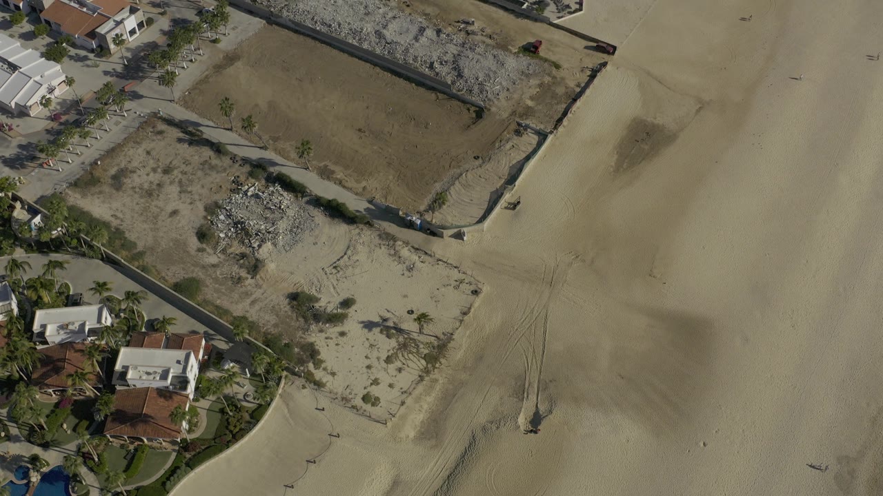 Aerial view of empty sand and walled beachfront parcels.
