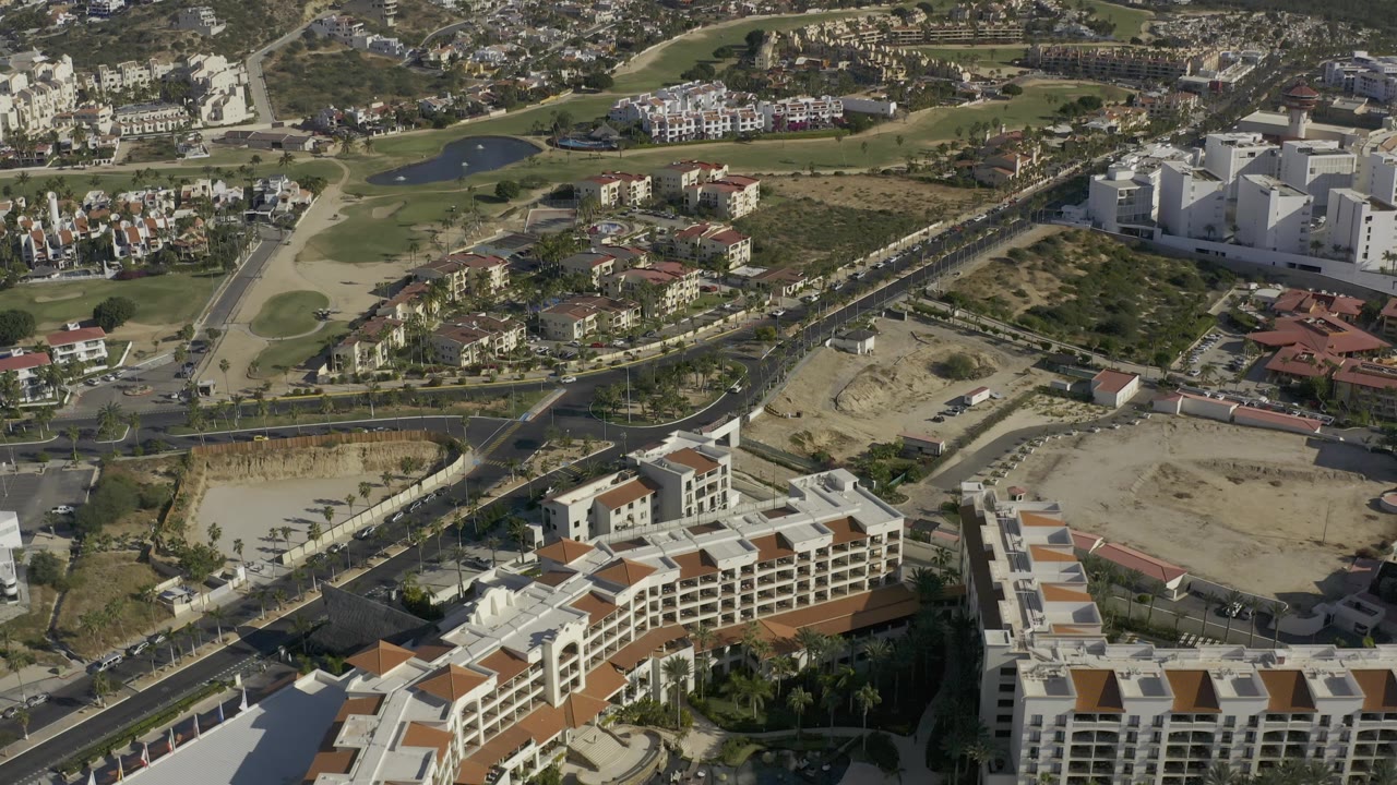 Aerial town view with resort buildings, roads, housing, and golf-course landscaping.