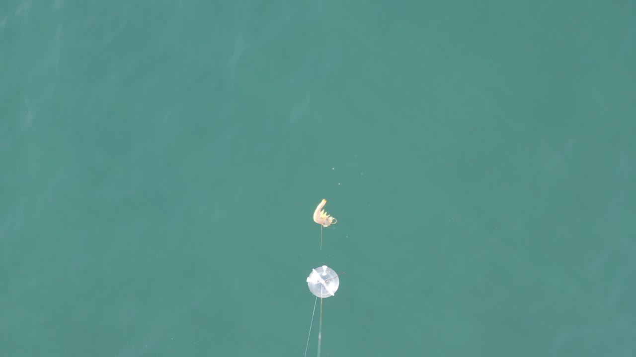 Fishing gear and small person over calm teal water.