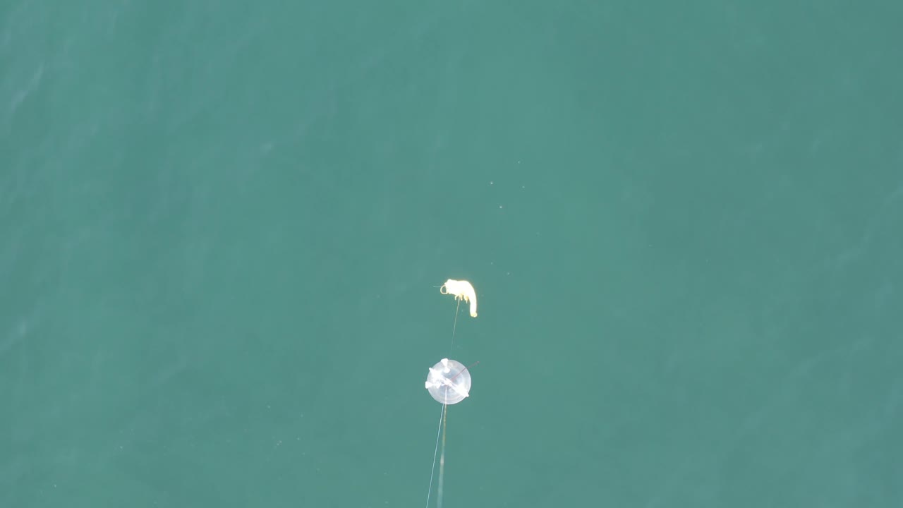 Overhead shot in Baja California Sur, Mexico with a pale floating object near the upper frame, faint tether-like lines below, and no visible people.