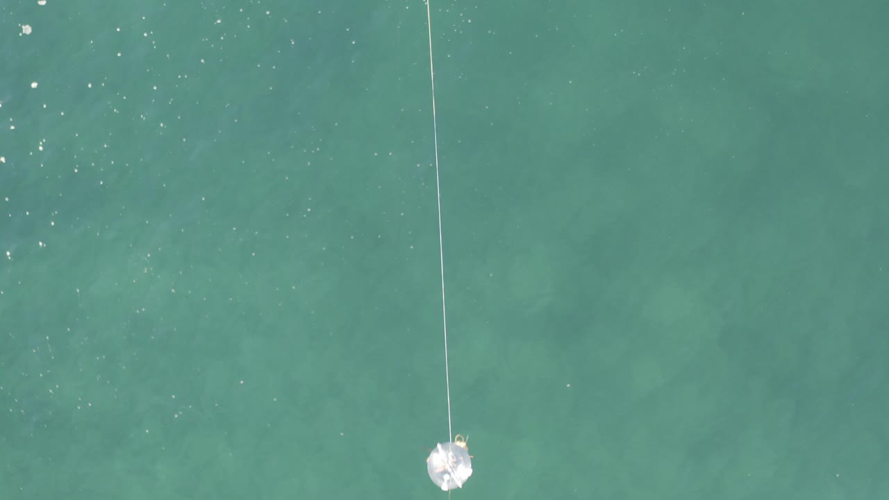 Overhead blue-green water with a fishing line and white lure near the surface.