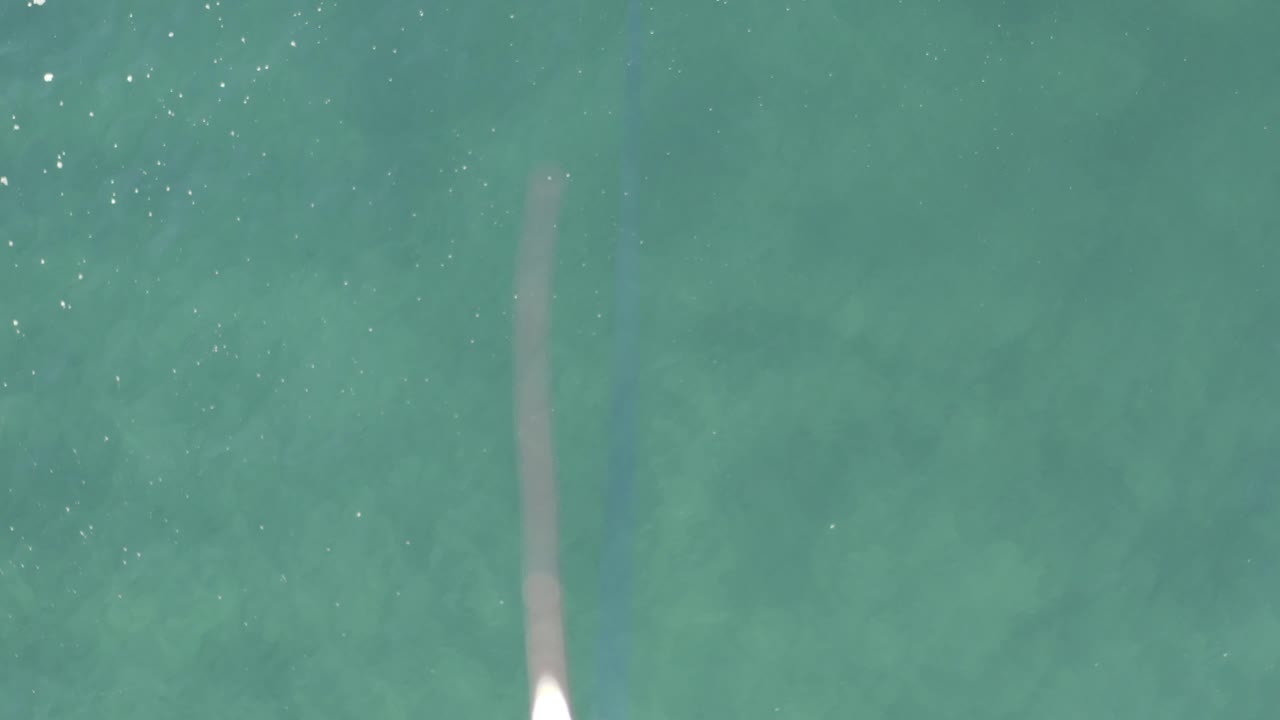 In this Baja California Sur Mexico frame, the lure sits near the lower-left edge while a pale underwater streak runs through the green water, with no visible people.